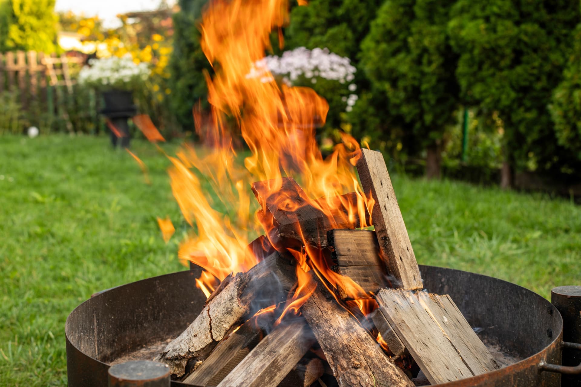 A fire burning in a garden fire pit at dusk