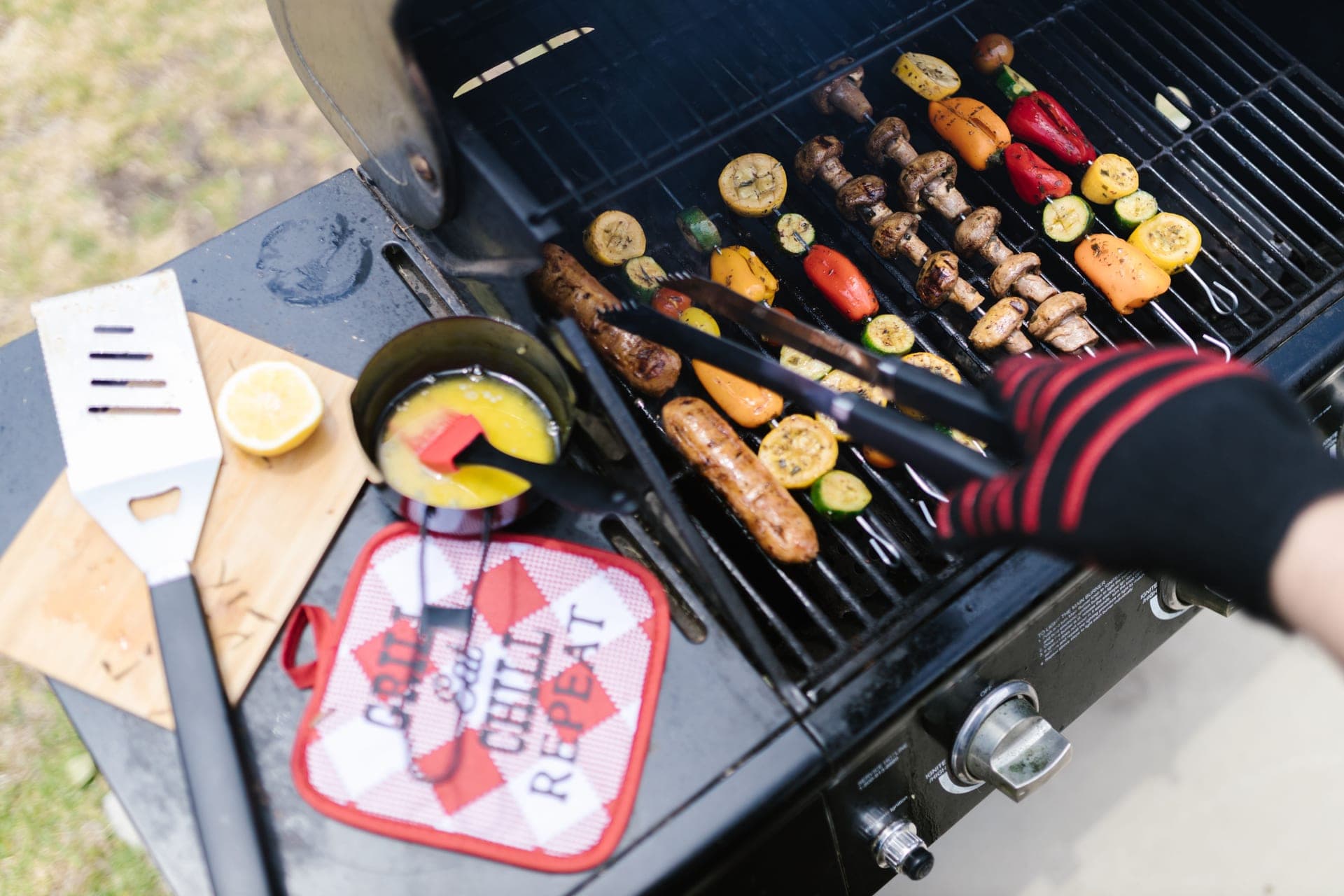 Heat-resistant gloves and tongs beside a hot outdoor cooker