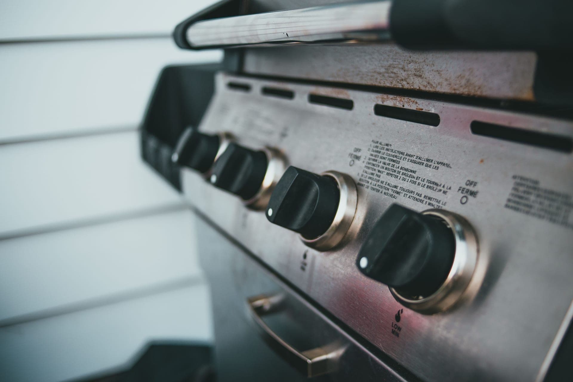 The control knobs and stainless panel of a four-burner gas grill