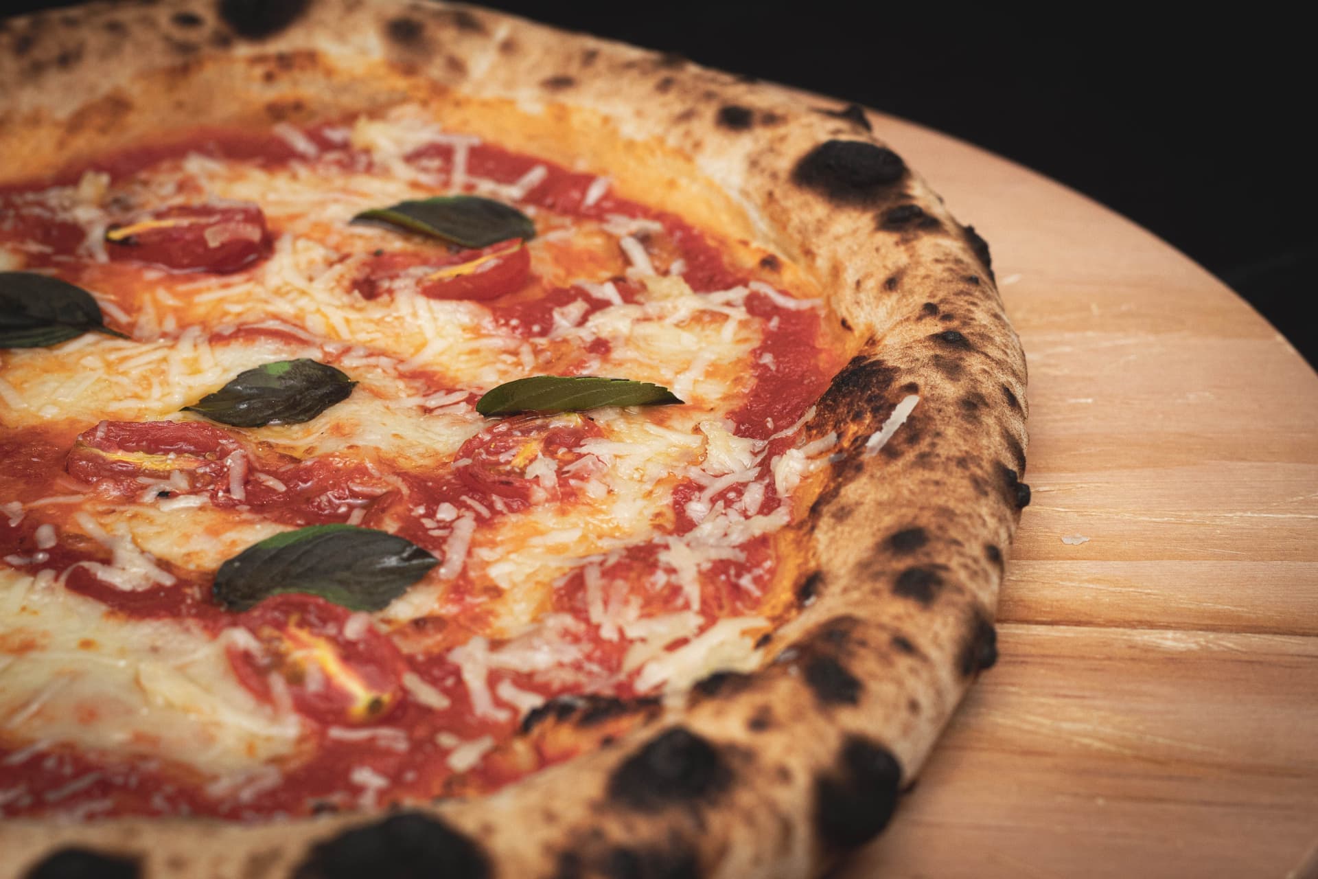 A leopard-spotted Neapolitan pizza on a wooden peel