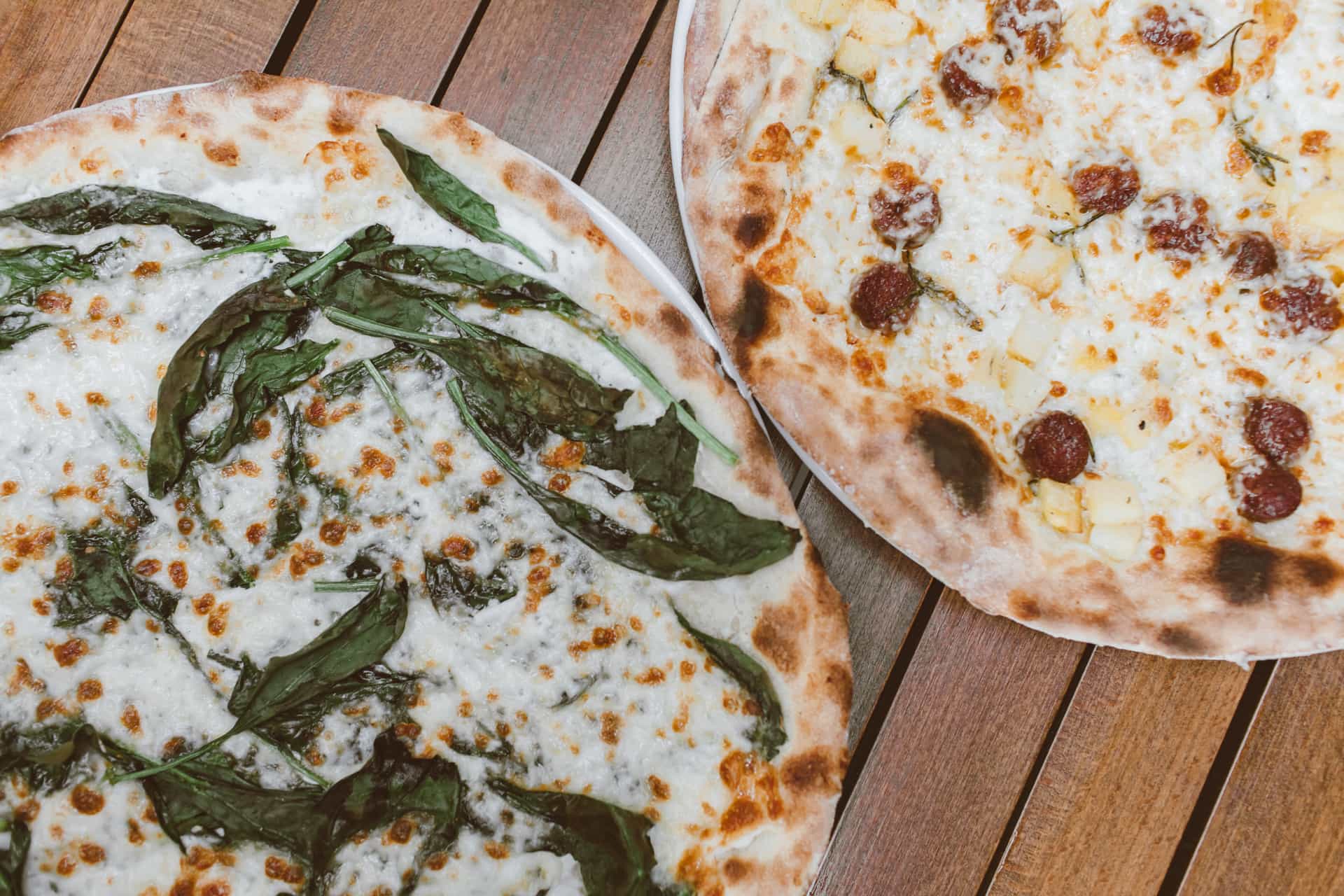 Two outdoor pizza ovens side by side on a patio