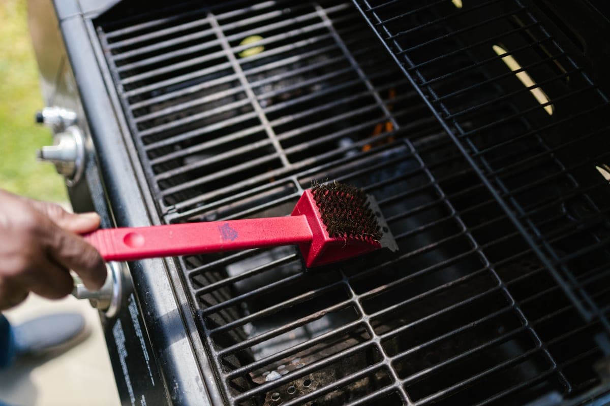 Cleaning an outdoor cooking appliance with a brush