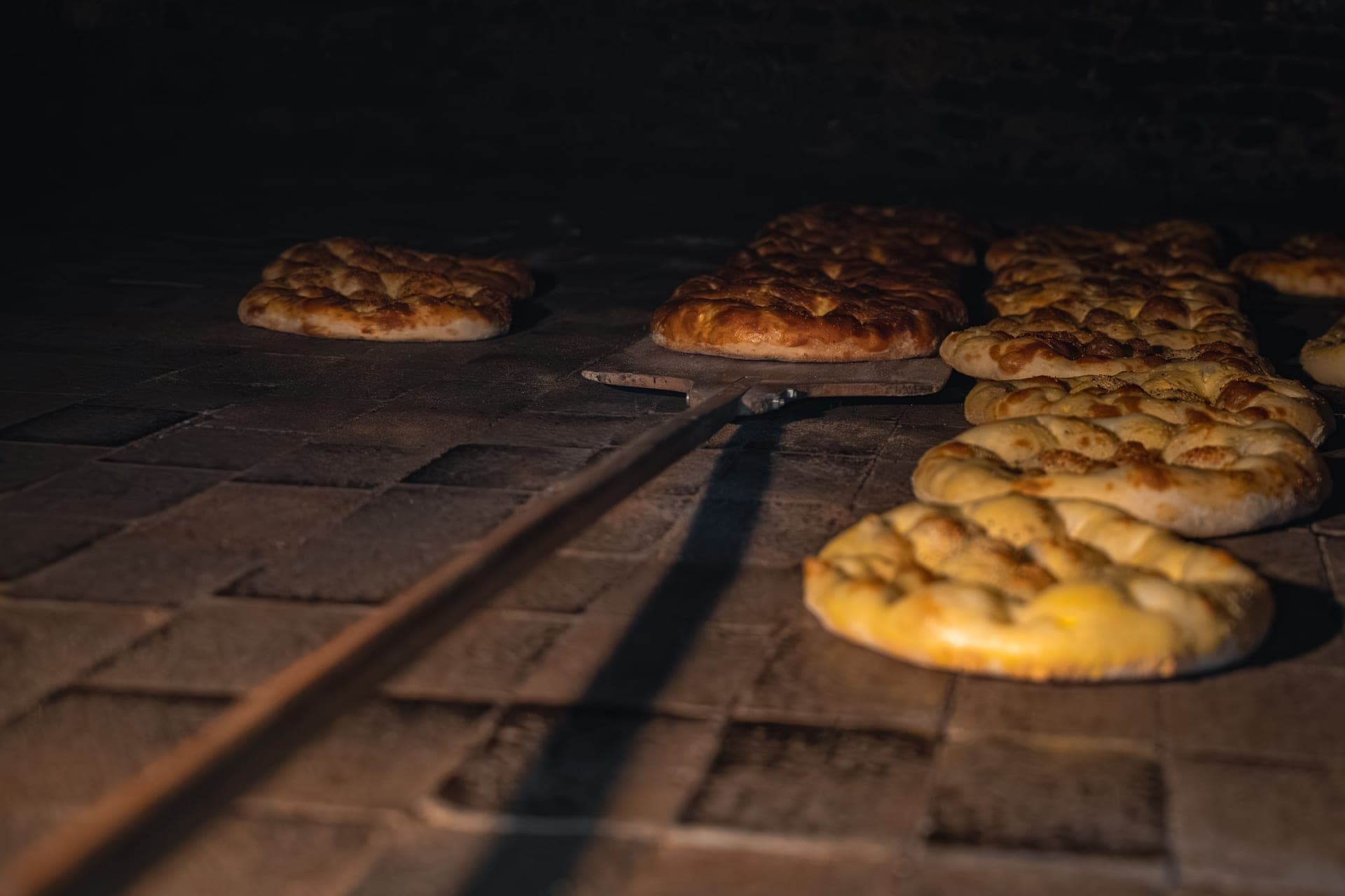Rustic bread loaves baking on the stone floor of a hot oven