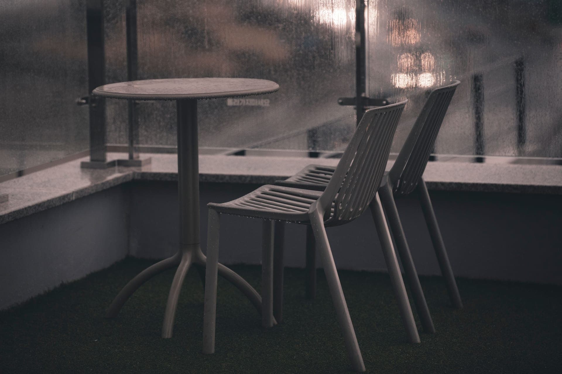 Rain beading on outdoor furniture on a balcony at dusk