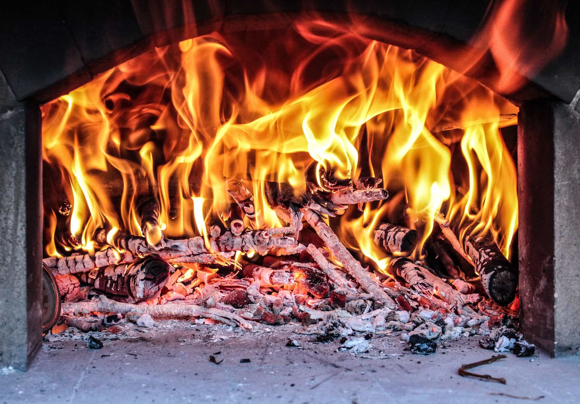 Small split wood burning inside a pizza oven