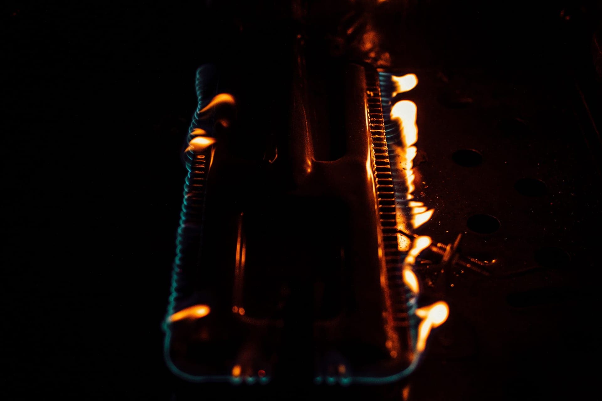 A gas burner alight inside a dark oven chamber